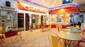 A restaurant interior with multiple tables and chairs, a counter with food items displayed, and a tiled floor. - Reddoorz @ The Providence Tower (Manila)