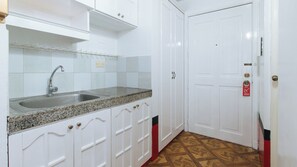 A kitchen with a granite countertop, white cabinets, and a double door with a red and black stripe. - Reddoorz @ The Providence Tower (Manila)