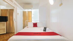 A hotel room with a bed, a TV, a red blanket, and a RedDoorz sign. - Reddoorz @ The Providence Tower (Manila)