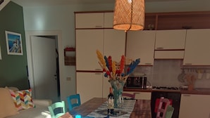 Een eetgedeelte met een houten tafel, blauwe stoelen en een hanglamp.