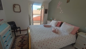 Een slaapkamer met een bed, een dressoir, een stoel en een raam.