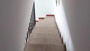 Een trap met een leuning aan de linkerkant en een muur met een lichtschakelaar aan de rechterkant.