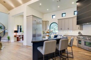 A modern kitchen with a central island, stainless steel appliances, and light-colored cabinetry.