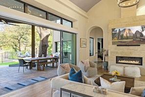 A spacious living area with a fireplace, comfortable seating, and a view of the outdoors. - Boaters and Golfers Dream Luxury Lakeside Villa (Sunrise Beach Village)