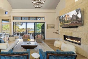A spacious living room with a fireplace, comfortable seating, and a large window overlooking a scenic view.