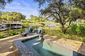 An outdoor swimming pool with lounge chairs and a view of a golf course and bridge.
