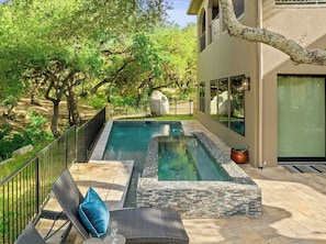 A swimming pool with a stone border, surrounded by a patio with lounge chairs and a glass enclosure. - Boaters and Golfers Dream Luxury Lakeside Villa (Sunrise Beach Village)
