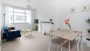 Un salon moderne avec un canapé bleu, une table à manger en bois et une grande fenêtre.