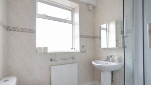 Une salle de bain avec des toilettes, un lavabo, une douche et une fenêtre.