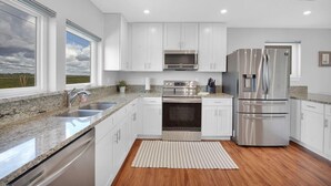A modern kitchen with white cabinets, stainless steel appliances, granite countertops, and a view of the outdoors. - Oceanfront 9BR Ponte Vedra Estate with Private Beach Access. Sleeps 20! (Ponte Vedra)