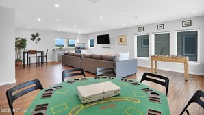 A modern living room with a dining table, sofas, and a foosball table. - Oceanfront 9BR Ponte Vedra Estate with Private Beach Access. Sleeps 20! (Ponte Vedra)