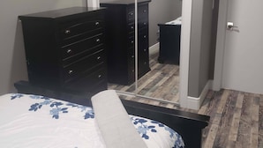 A bedroom with a bed, a dresser, a mirror, and a door.