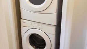 A stacked washer and dryer unit in a corner of a room.