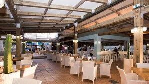 An outdoor dining area with wicker furniture and a tiled floor. - Mikes Beach Lux (Hersonissos)