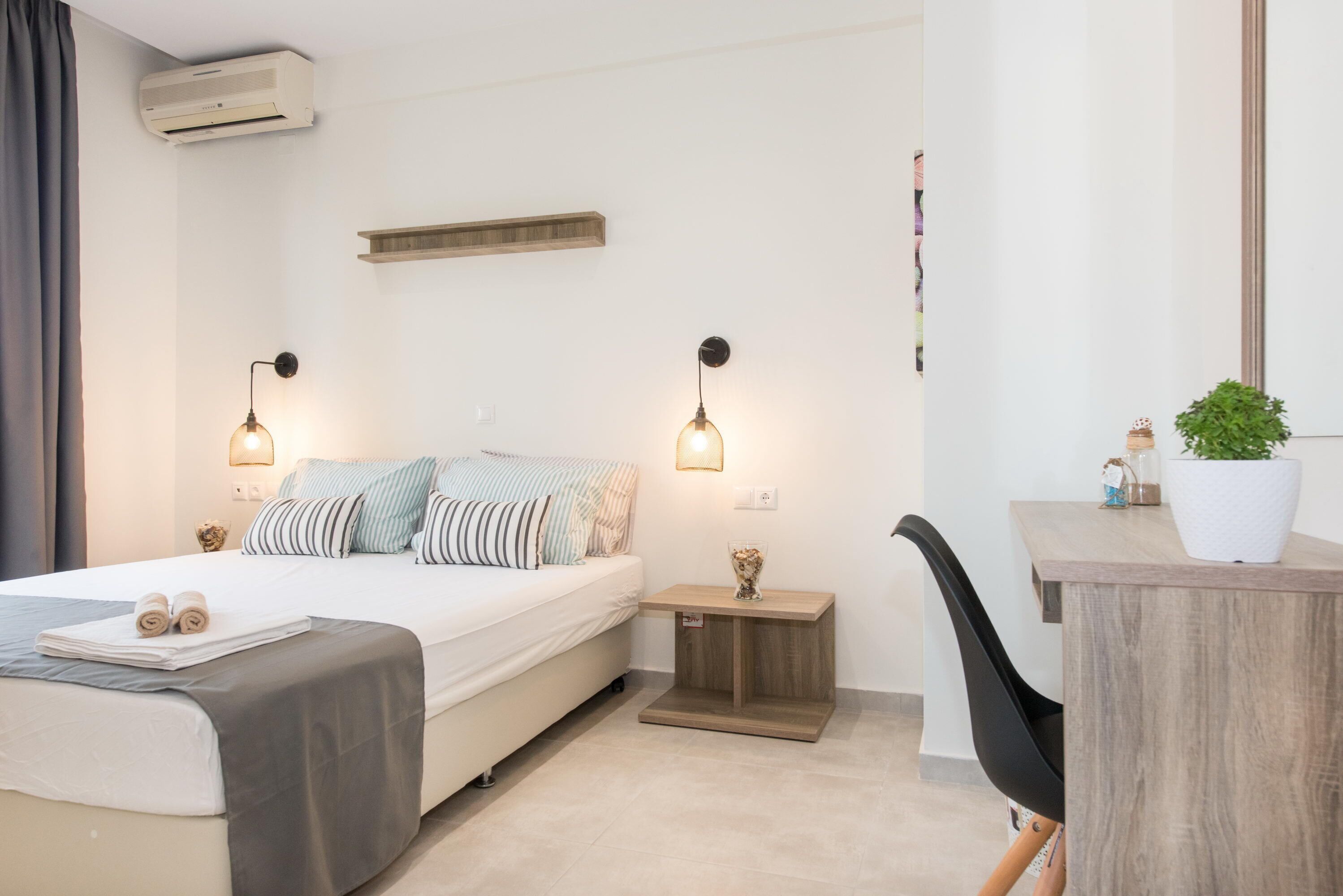A modern bedroom with a bed, bedside tables, a desk, and a chair.