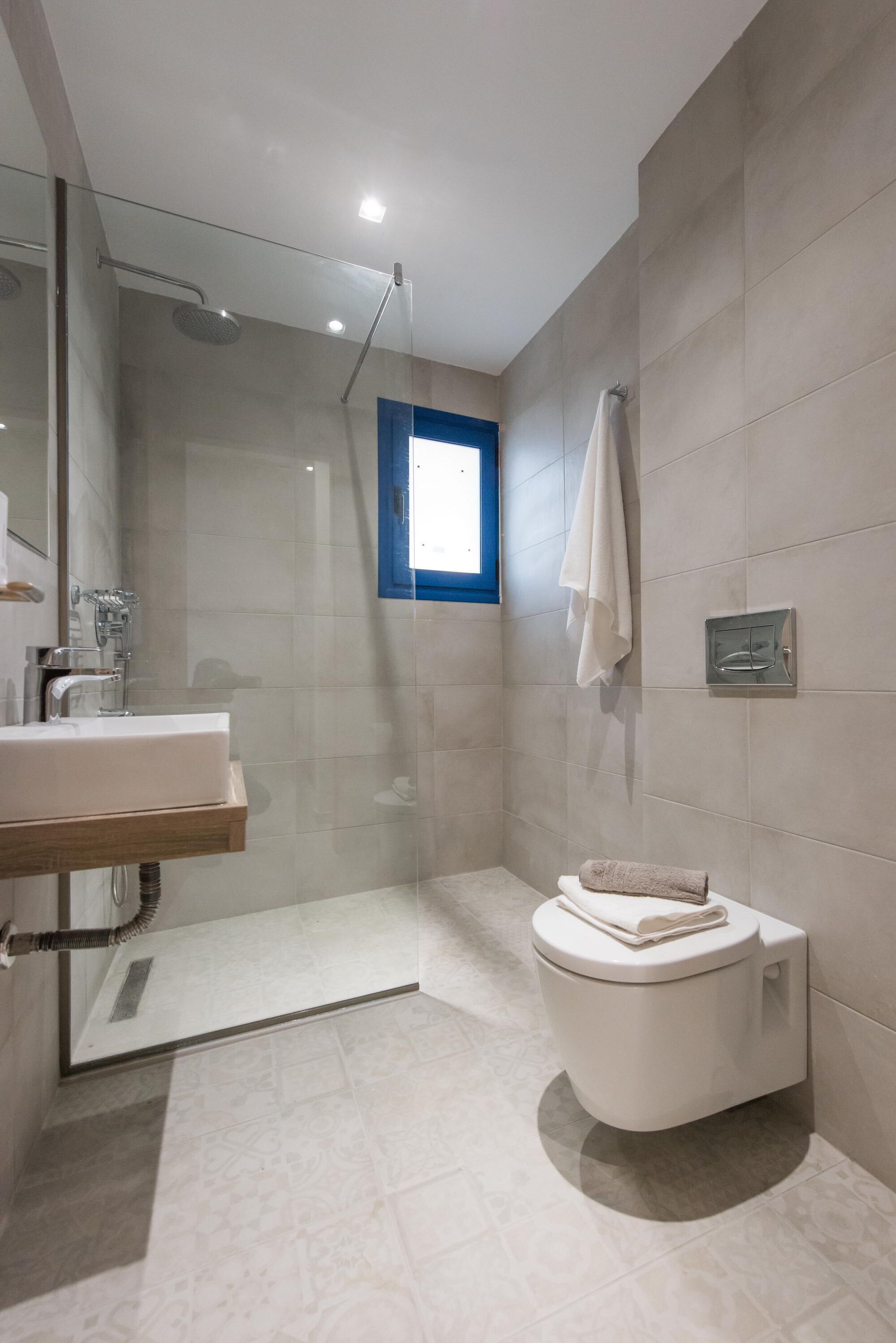 A modern bathroom with a glass-enclosed shower, a white toilet, and a sink with a wooden countertop.