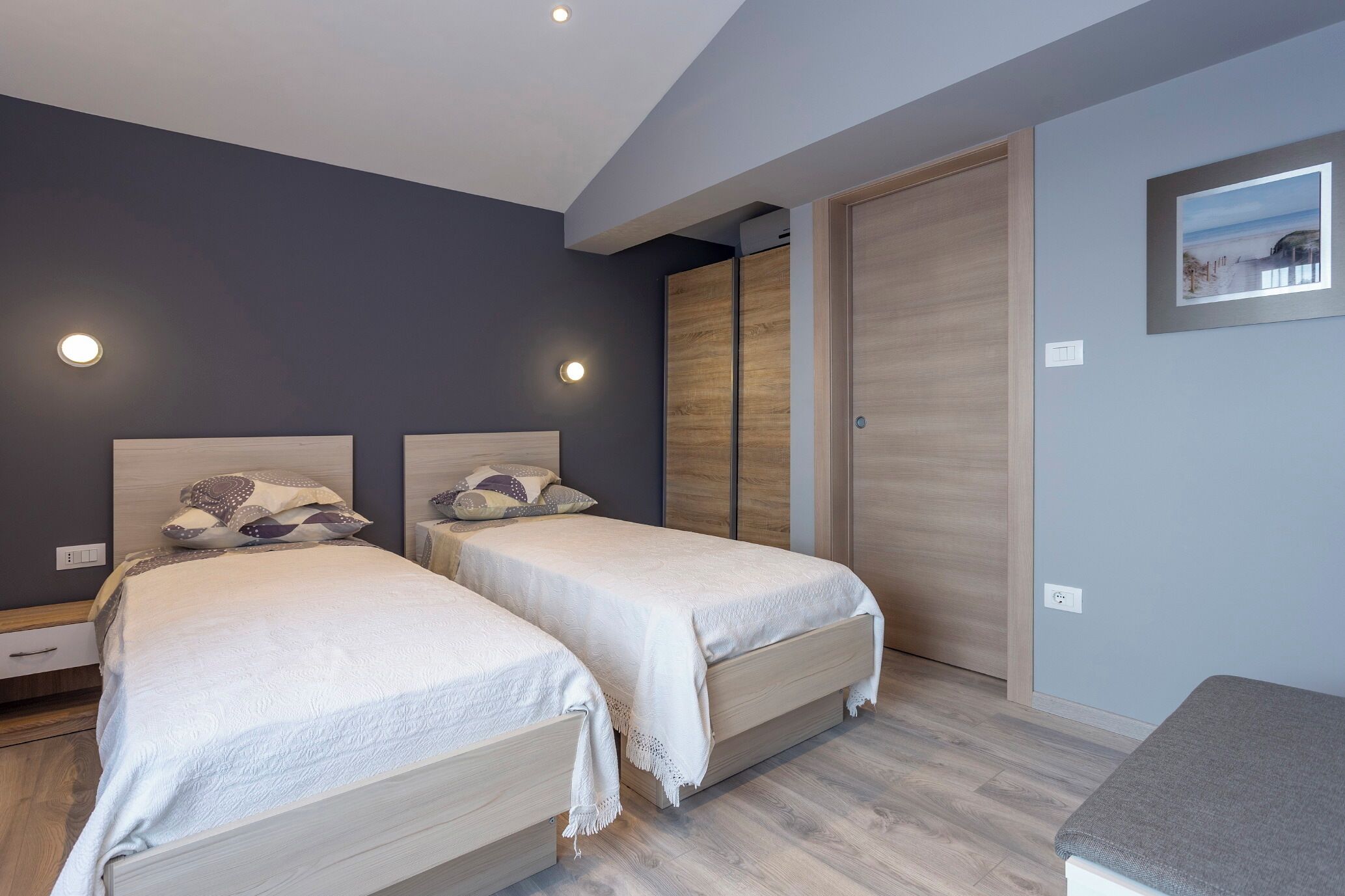 Un dormitorio moderno con dos camas, un armario de madera y un cuadro en la pared.