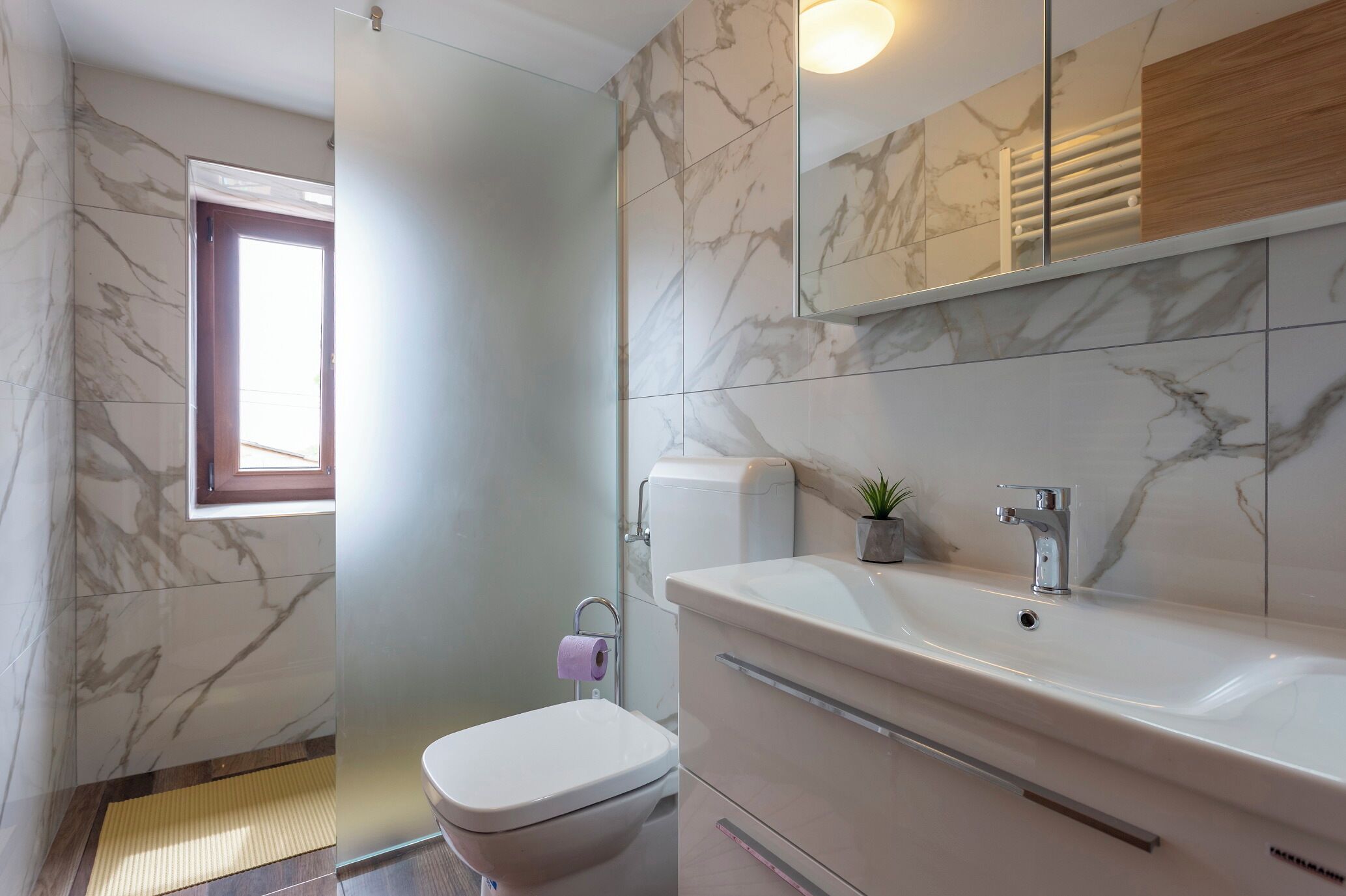 A bathroom with a toilet, sink, and mirror.