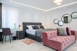 A modern bedroom with a bed, a desk, a chair, and a pink sofa.