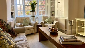 A cozy living room with a large window, a wooden coffee table, and two striped armchairs. - Beautiful 17th Century Coach House (Marlborough)