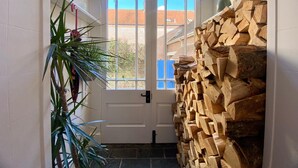 A hallway with a white door, a large window, and a stack of firewood. - Beautiful 17th Century Coach House (Marlborough)