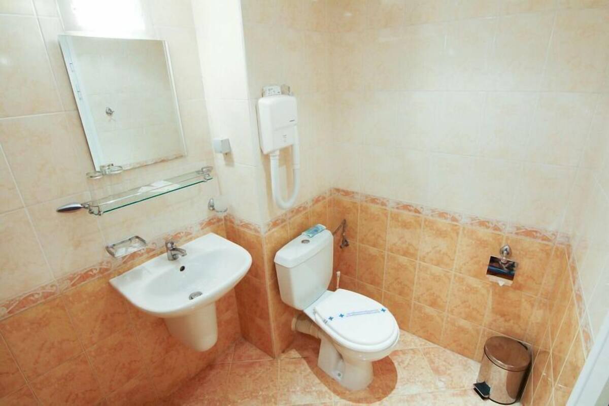 A bathroom with a sink, toilet, and mirror.