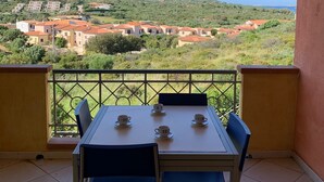 Ein Balkon mit Tisch und Stühlen, der auf einen Wohnbereich mit Häusern und Grünflächen blickt.