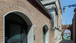 A narrow brick alley with arched doorways and a blue mat at the entrance.