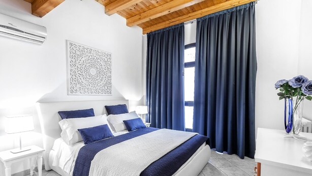 A bedroom with a bed, nightstands, a desk, and a window with curtains.
