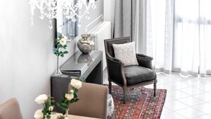 A modern living room with a dark leather armchair, a chandelier, a vase with flowers, and a patterned rug. - Starfish 4         . (Venezia)