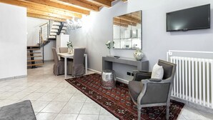 A modern living room with a wooden ceiling, a flat-screen TV, a large mirror, a dining area with a table and chairs, and a patterned rug. - Starfish 4         . (Venezia)