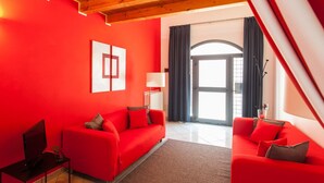 A modern living room with a red sofa set, a flat-screen TV, and a wooden ceiling.