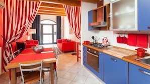 A modern kitchen with blue cabinets, a wooden countertop, and red curtains.