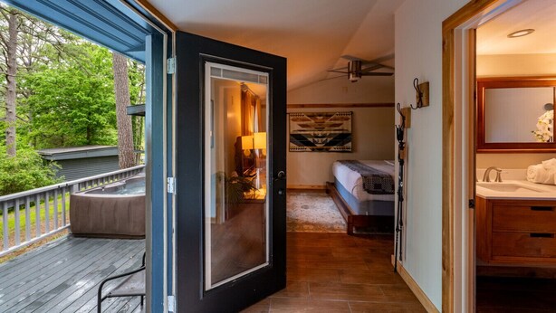 A bedroom with a bed, a nightstand, a window, and a view of the outdoors.