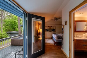 A bedroom with a bed, a nightstand, a window, and a view of the outdoors. - Camphouse with Hot Tub, Kitchen, King, Pullout (Eureka Springs)
