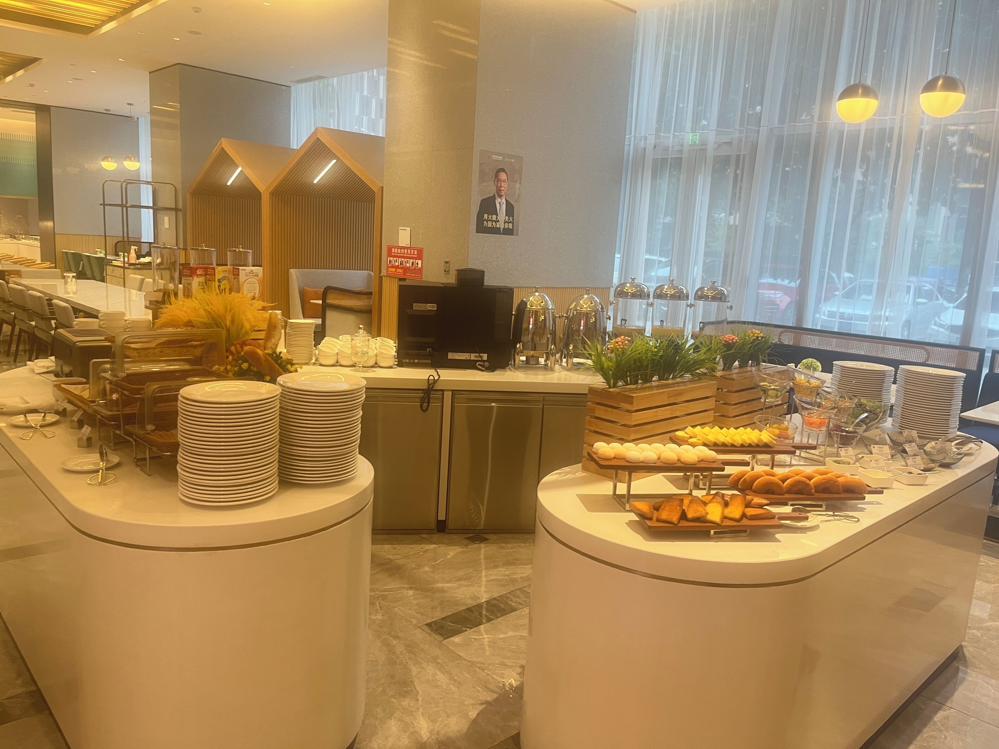 A hotel breakfast area with a buffet setup, including plates, bowls, and various food items.