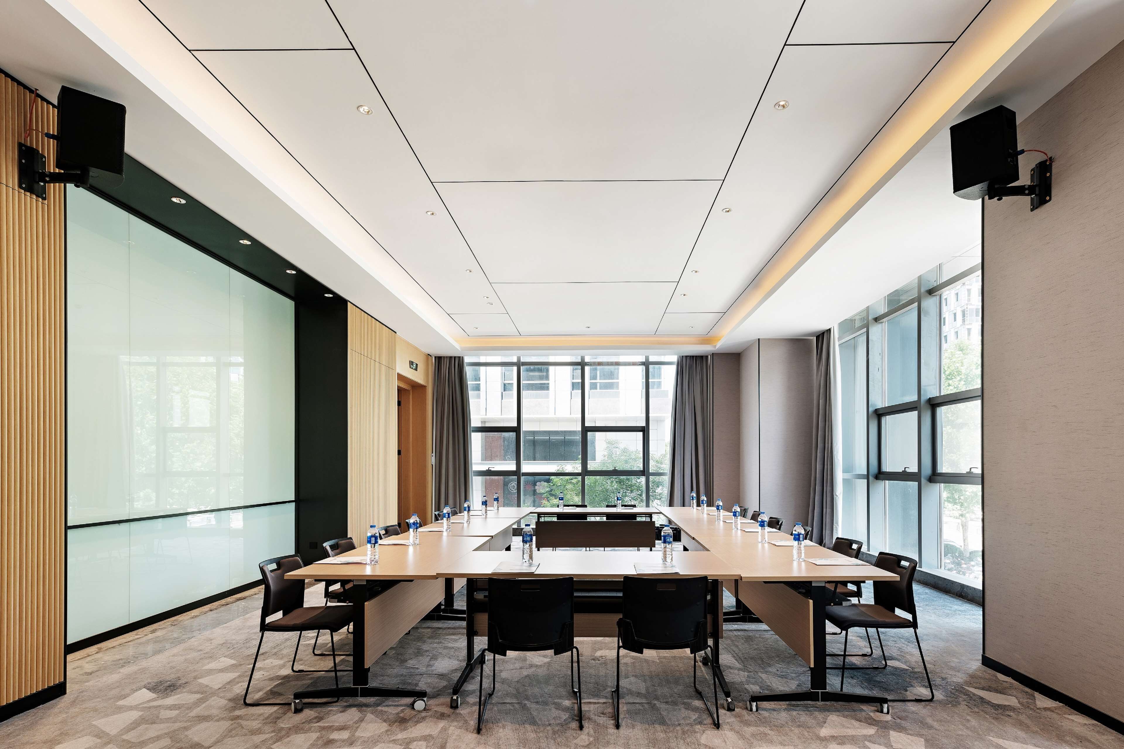 A conference room with a long table, chairs, and a projector screen.
