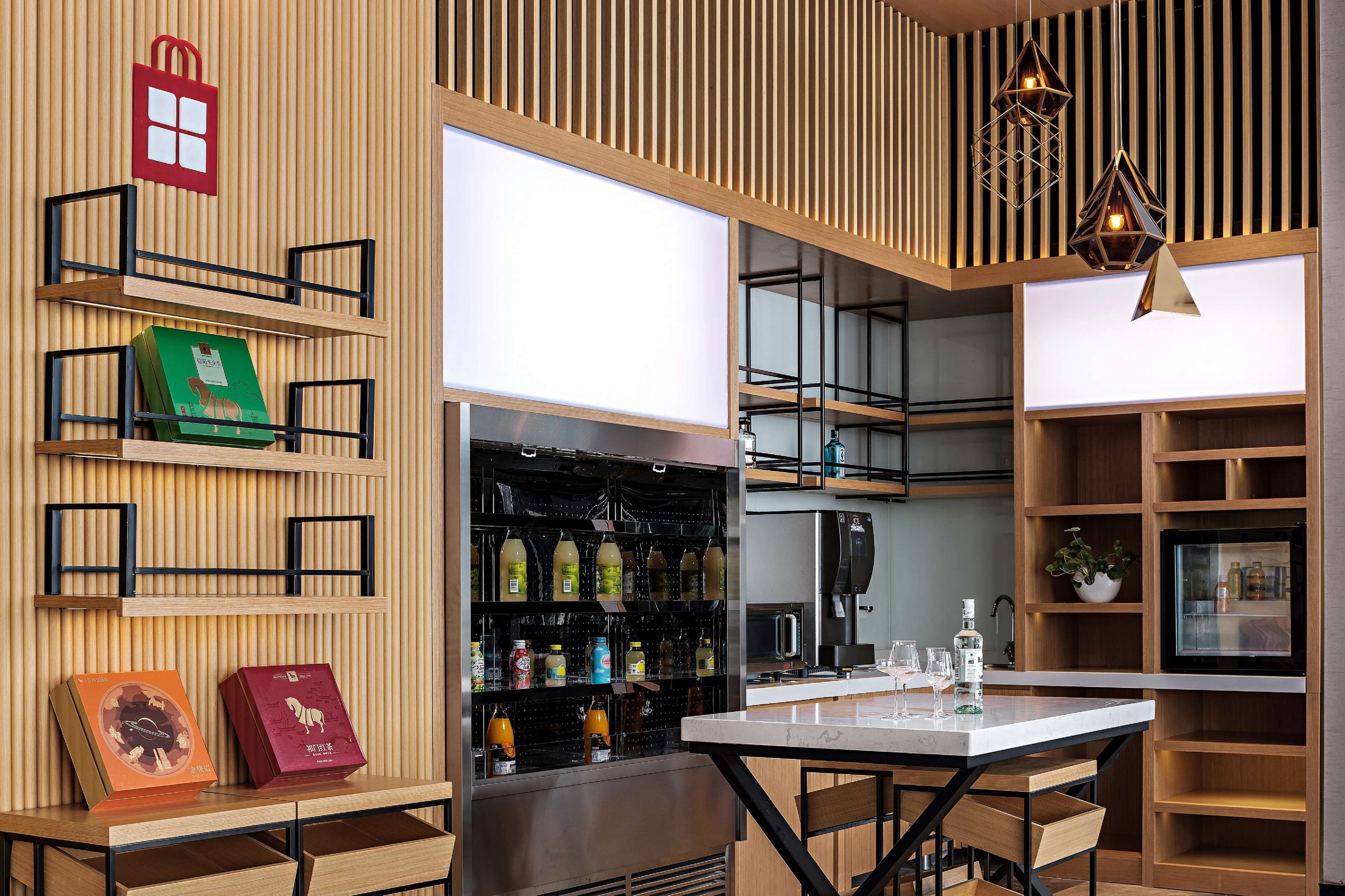 A modern kitchen with wooden shelves, a dining table, and hanging pendant lights.