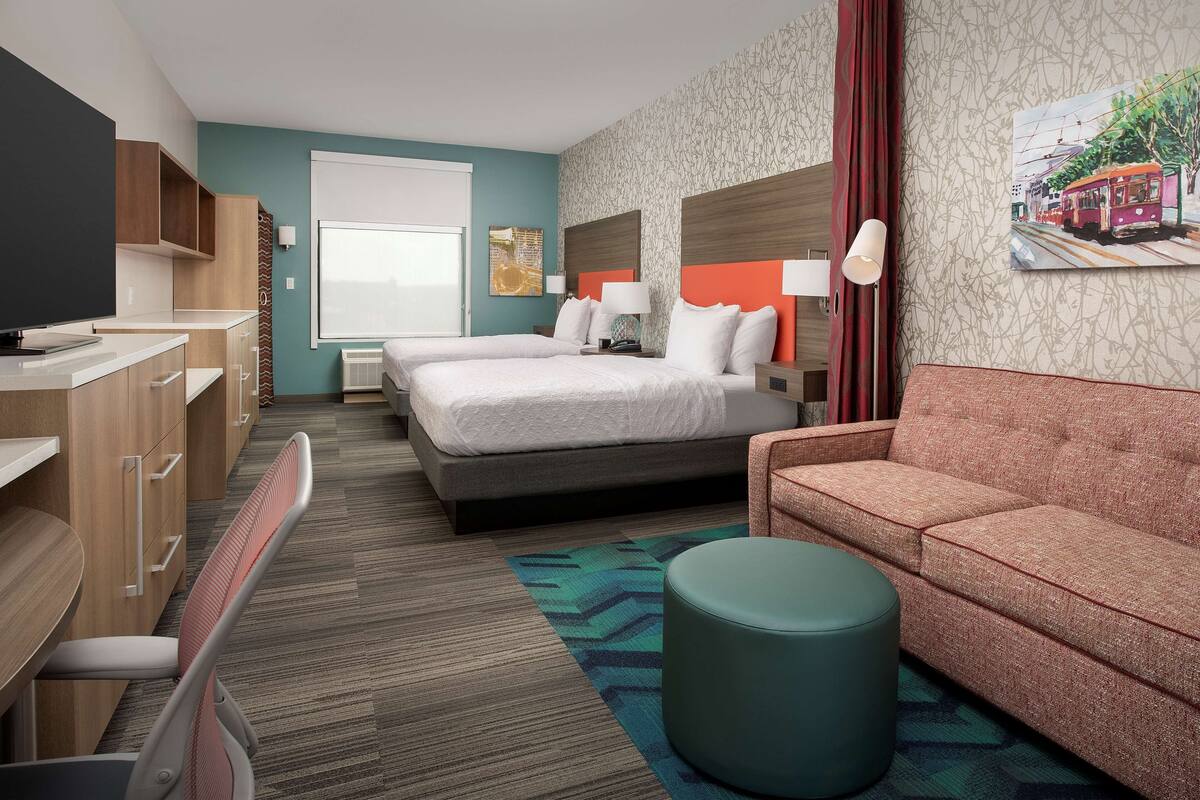 A hotel room with a bed, a sofa, a desk, and a TV.