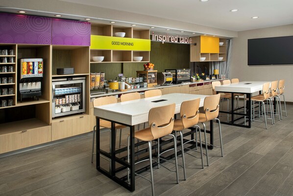 A modern restaurant with a bar area, seating, and a large screen.