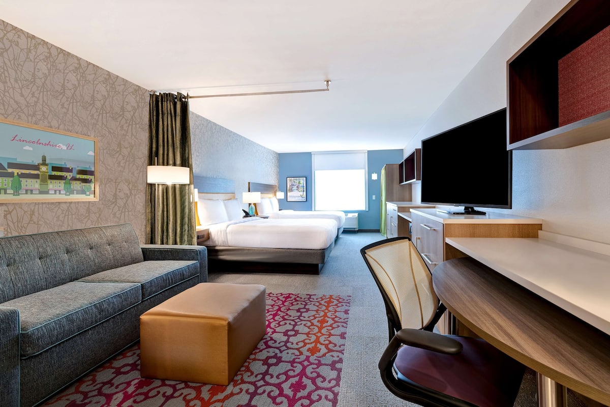 Una camera d'albergo con un divano, un letto, una scrivania, una sedia e una televisione.