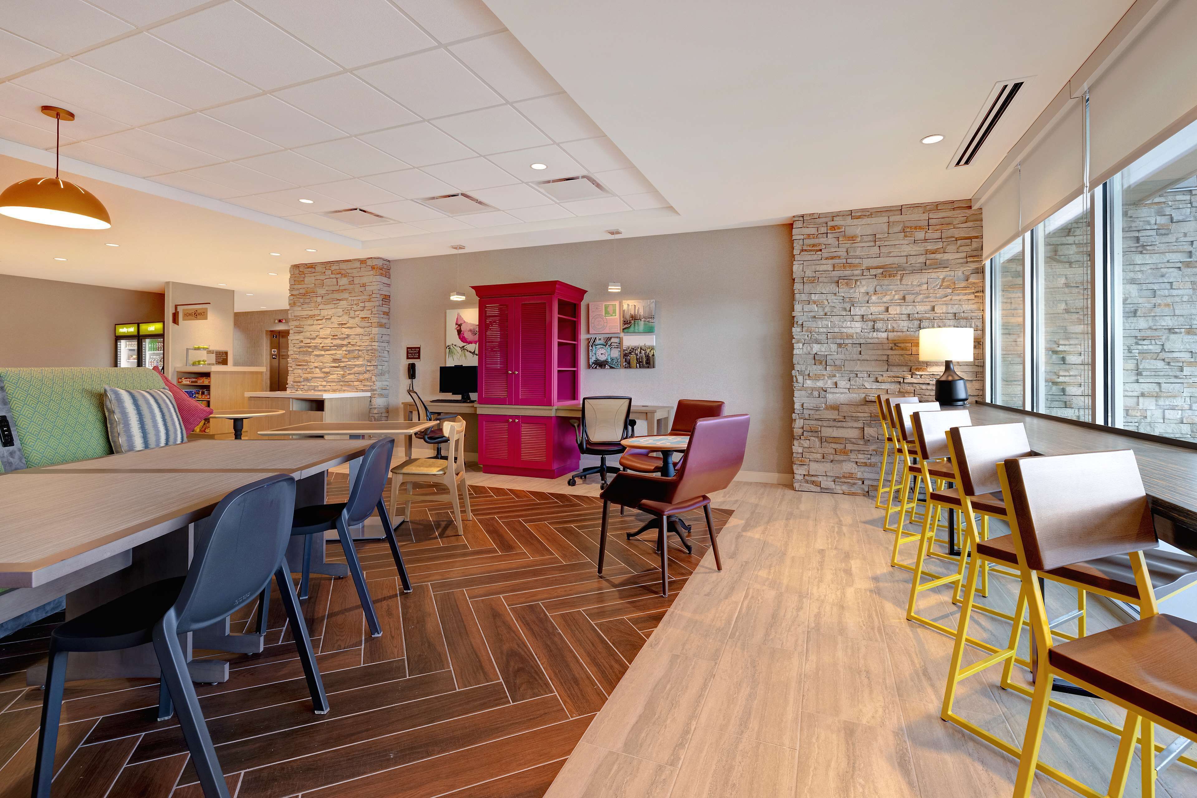 A modern hotel lobby with a long reception desk, seating area, and a stone accent wall.