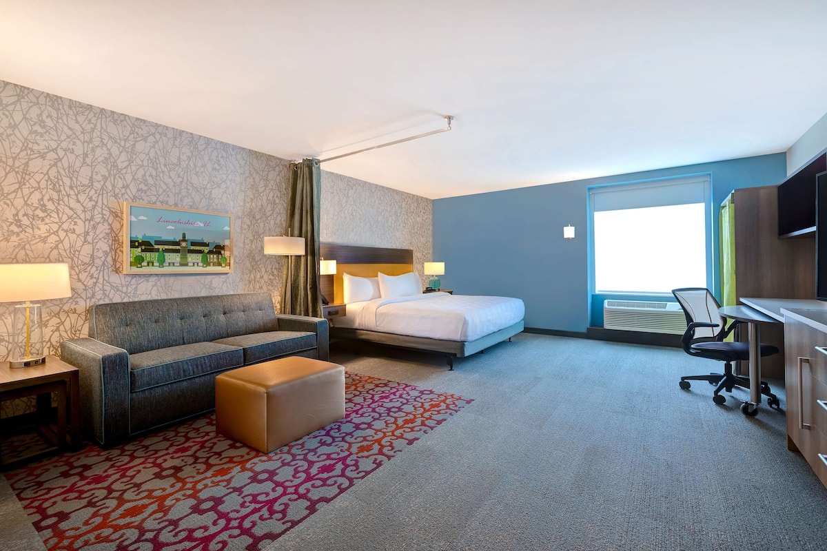 Una camera d'albergo con un letto, un divano, una scrivania e una sedia.