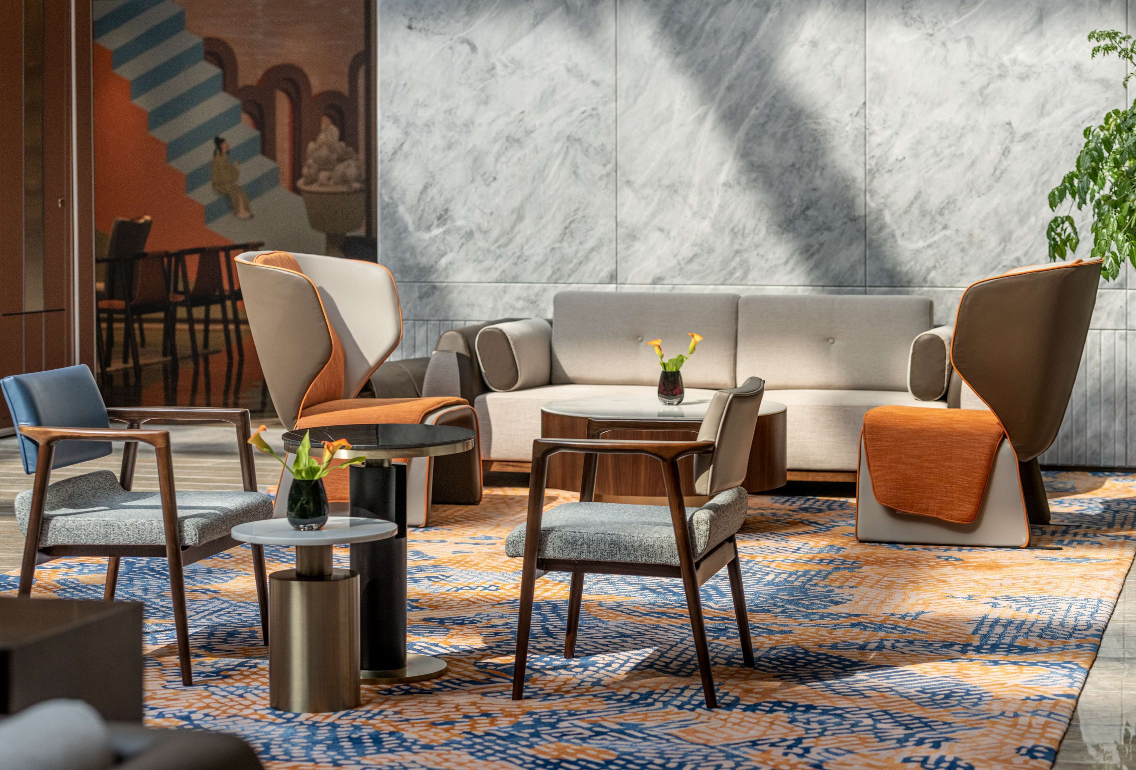 A modern lounge area with a sofa, armchairs, a coffee table, and a patterned rug.