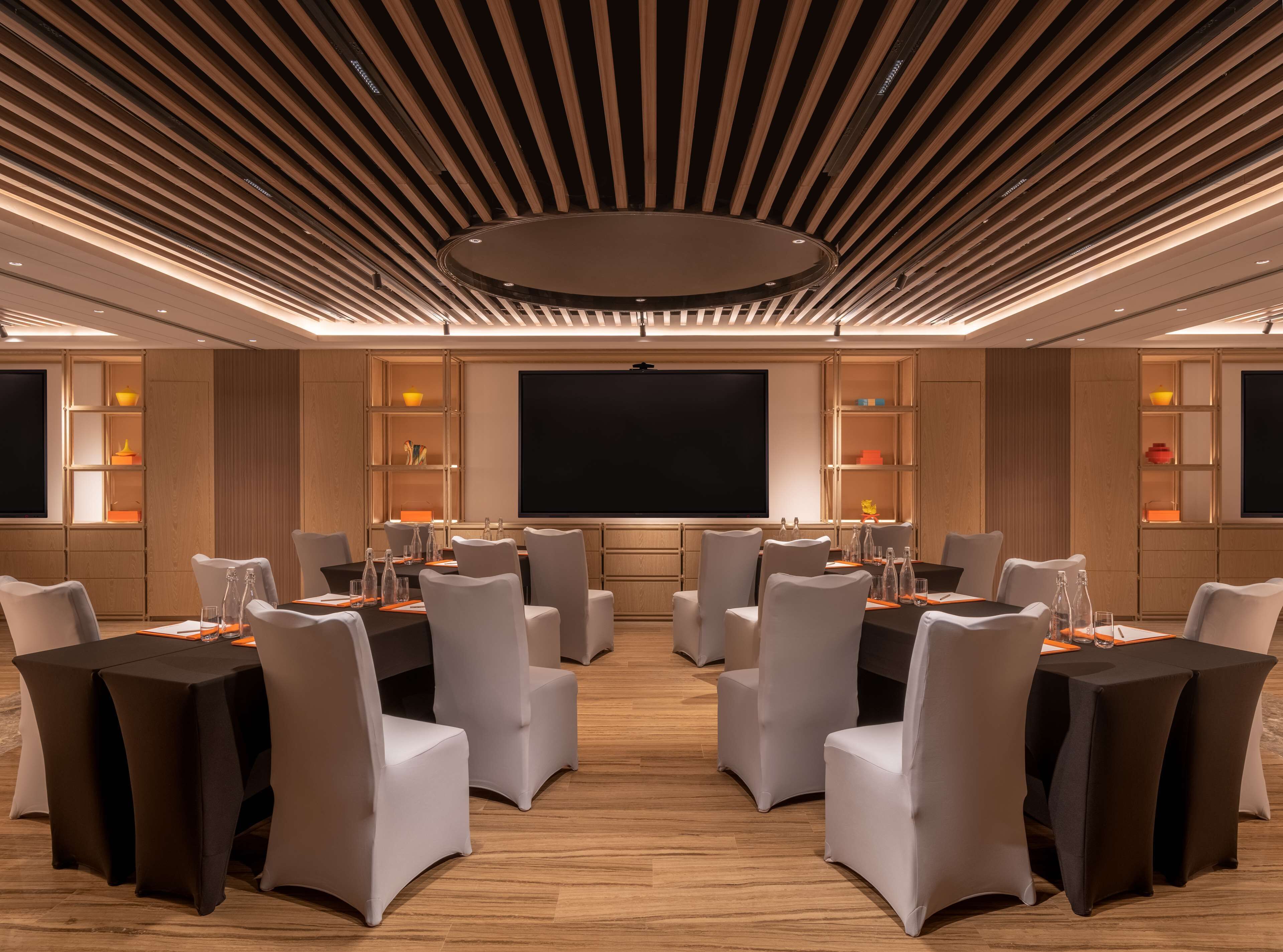 A conference room with a large screen, multiple tables, and chairs.