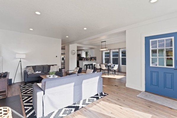 A modern living room with a sofa, coffee table, and dining area with chairs.