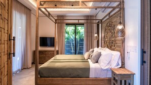 Een moderne slaapkamer met een hemelbed van hout, een flatscreen-televisie en uitzicht op groen.