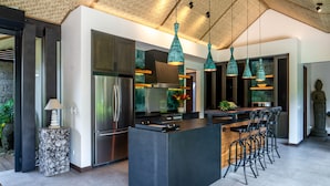 Een moderne keuken met een centraal kookeiland, roestvrijstalen apparatuur en hangende吊灯