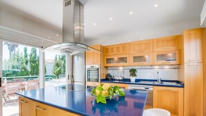 Een moderne keuken met houten kastjes, een roestvrijstalen afzuigkap en een groot eiland met een glazen blad.