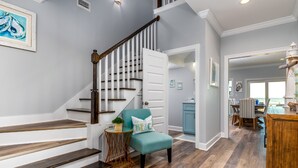 A staircase with wooden steps and a white door, a teal armchair with a cushion, and a small round table with a plant. - Blue Pearl | great august rates. Pool. Hottub. On Beach (Dauphin Island)